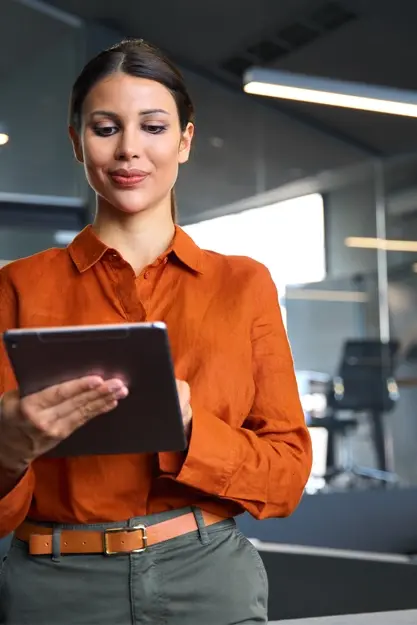 Dark haired woman in orange shirt using tablet Dark haired woman in orange shirt using tablet