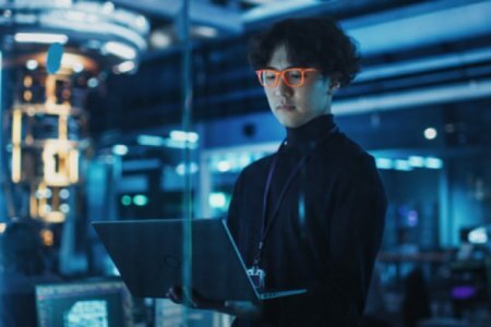 A professional in a high-tech lab environment using a laptop, representing the development of quantum computing applications